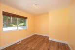 This empty room features warm yellow walls and a beautiful wood-look laminate floor, creating a bright and inviting atmosphere.