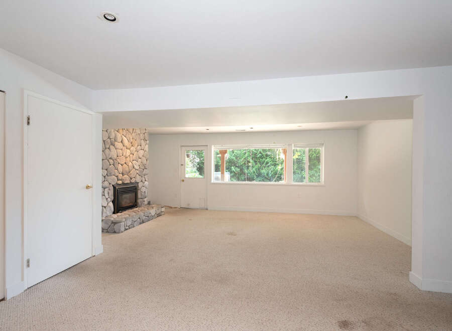 Discover comfort and style in this spacious living area, featuring a striking stone fireplace as the focal point.