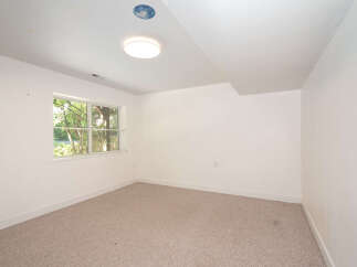 This spacious room features a large window offering abundant natural light and views of lush greenery.