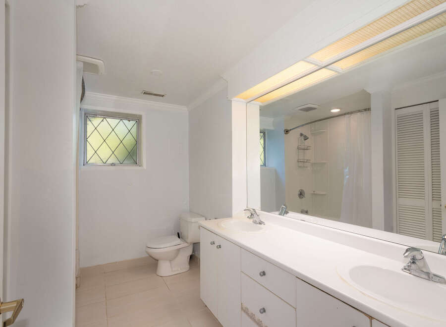 This bathroom features a spacious double vanity with ample counter space and storage, perfect for any household.