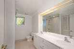 This bathroom features a spacious double vanity with ample counter space and storage, perfect for any household.
