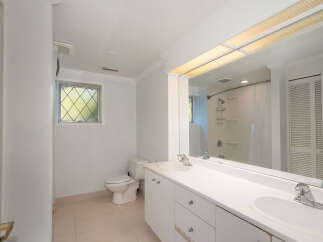 This bathroom features a spacious double vanity with ample counter space and storage, perfect for any household.