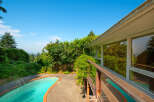 Enjoy a refreshing dip in the sparkling pool, surrounded by lush greenery and mature trees.