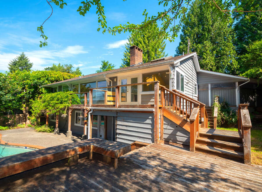 Enjoy outdoor living with this charming home featuring a spacious wooden deck and a sparkling swimming pool, perfect for entertaining or relaxing.