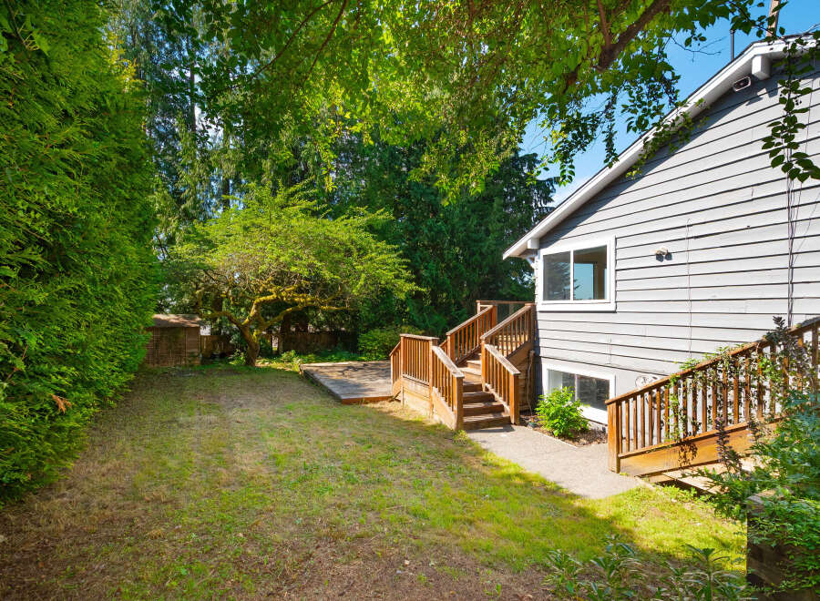 Enjoy outdoor living in this spacious backyard featuring a large wooden deck perfect for entertaining and a lush green lawn.