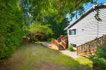 Enjoy outdoor living in this spacious backyard featuring a large wooden deck perfect for entertaining and a lush green lawn.