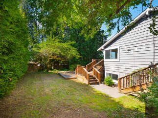 Enjoy outdoor living in this spacious backyard featuring a large wooden deck perfect for entertaining and a lush green lawn.
