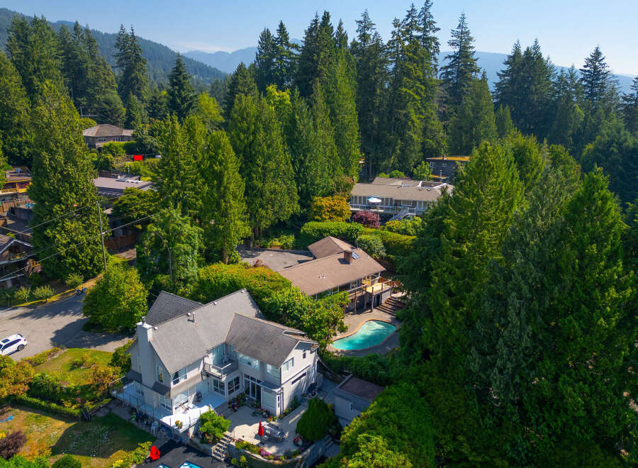 Nestled amidst lush greenery and towering trees, this stunning property offers a private oasis with a sparkling swimming pool and expansive outdoor living spaces.