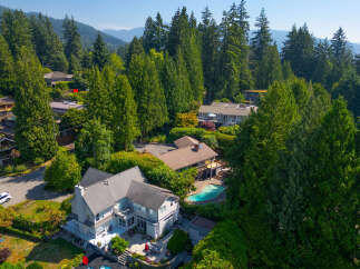 Nestled amidst lush greenery and towering trees, this stunning property offers a private oasis with a sparkling swimming pool and expansive outdoor living spaces.