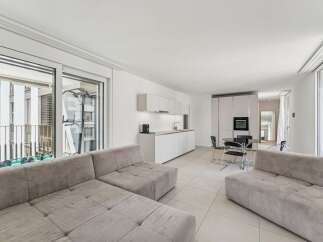 Experience modern living in this bright and airy open-concept apartment, featuring a sleek white kitchen with integrated appliances and ample counter space.