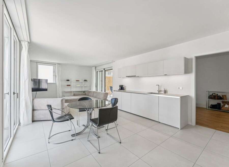 Experience modern living in this bright and airy open-concept space, featuring a sleek white kitchen with ample cabinet space and a stylish dining area.