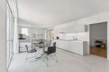 Experience modern living in this bright and airy open-concept space, featuring a sleek white kitchen with ample cabinet space and a stylish dining area.