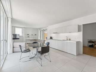 Experience modern living in this bright and airy open-concept space, featuring a sleek white kitchen with ample cabinet space and a stylish dining area.