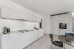 Experience modern living in this sleek, white kitchen featuring integrated appliances and ample cabinet space.