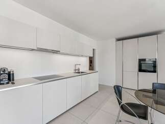 Experience modern living in this sleek, white kitchen featuring integrated appliances and ample cabinet space.