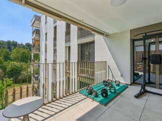 Enjoy your personal fitness sanctuary on this spacious balcony, complete with a weight rack, dumbbells, and kettlebells.