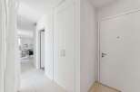 Step into this bright and airy hallway, featuring sleek white walls and a pristine tiled floor.