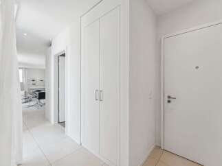 Step into this bright and airy hallway, featuring sleek white walls and a pristine tiled floor.