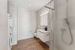 This modern bathroom features a stacked washer and dryer for ultimate convenience.