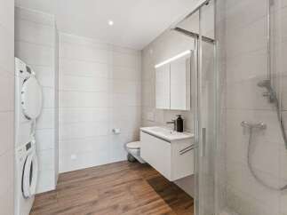 This modern bathroom features a stacked washer and dryer for ultimate convenience.