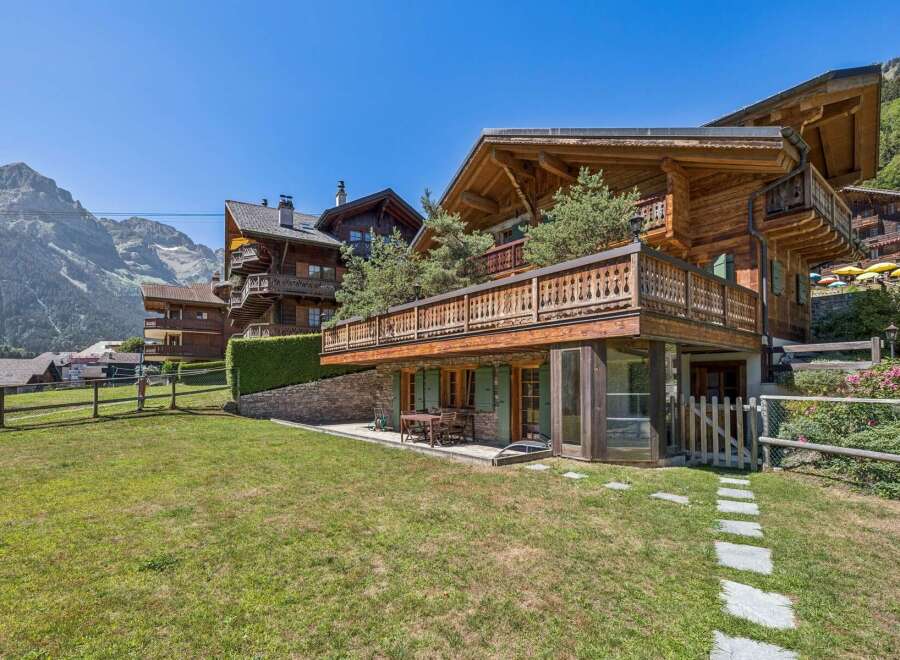 Experience luxurious alpine living in this stunning wooden chalet, featuring expansive balconies with intricate railings and breathtaking mountain views.