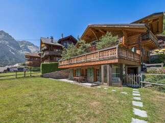 Experience luxurious alpine living in this stunning wooden chalet, featuring expansive balconies with intricate railings and breathtaking mountain views.