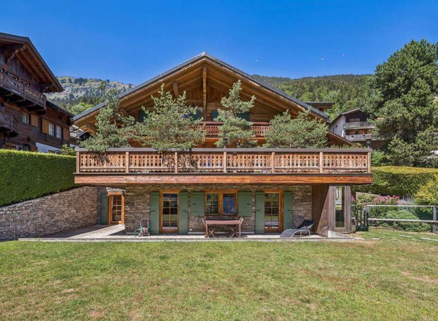 Experience luxurious alpine living in this stunning chalet, featuring a grand wooden exterior and a spacious balcony perfect for enjoying mountain views.