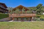 Experience luxurious alpine living in this stunning chalet, featuring a grand wooden exterior and a spacious balcony perfect for enjoying mountain views.