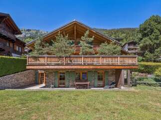 Experience luxurious alpine living in this stunning chalet, featuring a grand wooden exterior and a spacious balcony perfect for enjoying mountain views.