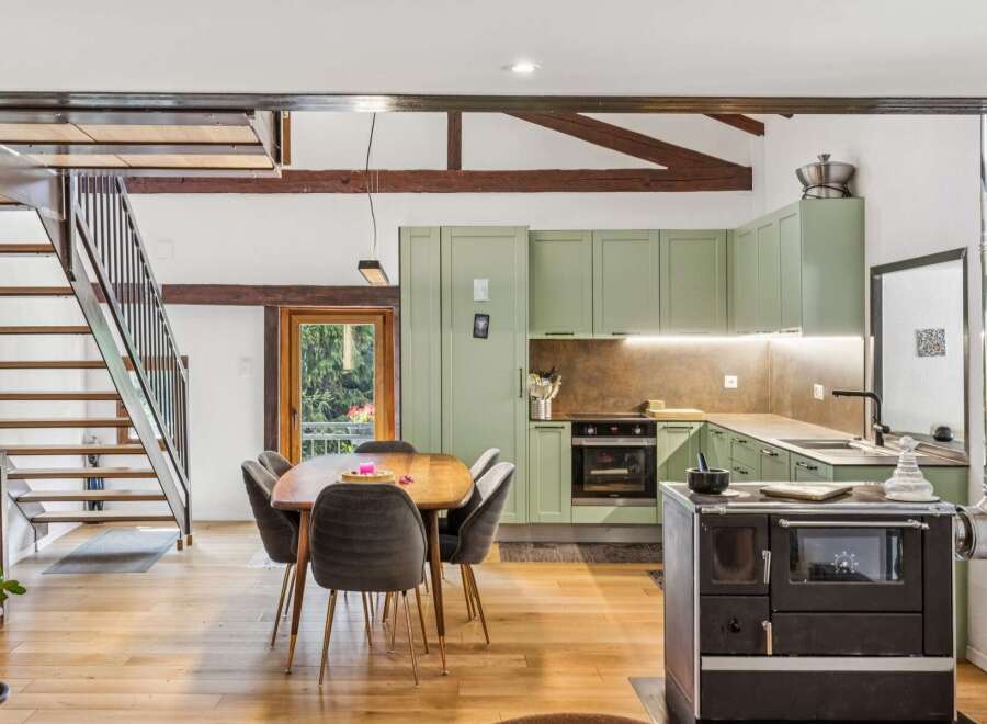 Discover this charming rustic kitchen and dining area, featuring exposed wooden beams and a modern green cabinetry set.