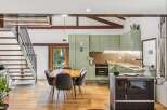 Discover this charming rustic kitchen and dining area, featuring exposed wooden beams and a modern green cabinetry set.