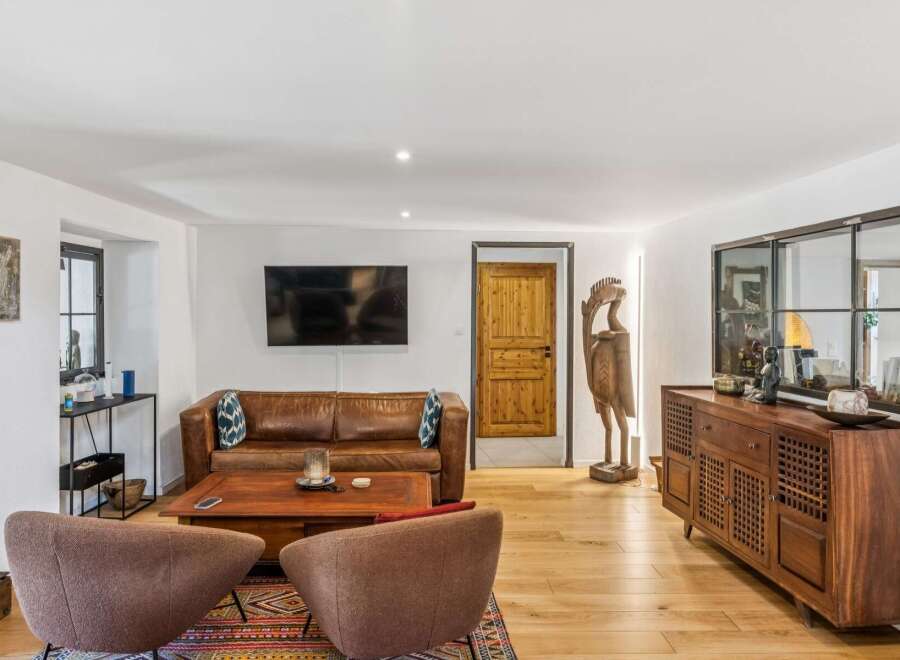 This inviting living room features a luxurious brown leather sofa complemented by a stylish wooden coffee table and two cozy armchairs.