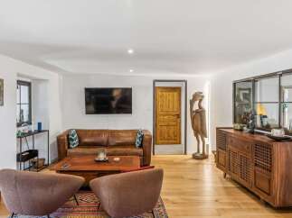 This inviting living room features a luxurious brown leather sofa complemented by a stylish wooden coffee table and two cozy armchairs.