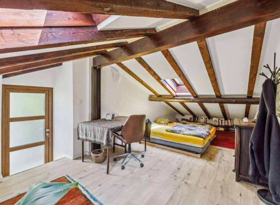 Discover this charming attic bedroom featuring exposed wooden beams and a skylight for natural light.