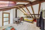 Discover this charming attic bedroom featuring exposed wooden beams and a skylight for natural light.