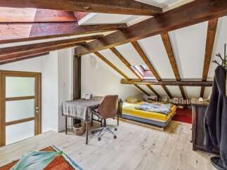 Discover this charming attic bedroom featuring exposed wooden beams and a skylight for natural light.