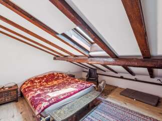 Discover this charming attic bedroom featuring exposed wooden beams and a skylight that floods the space with natural light.