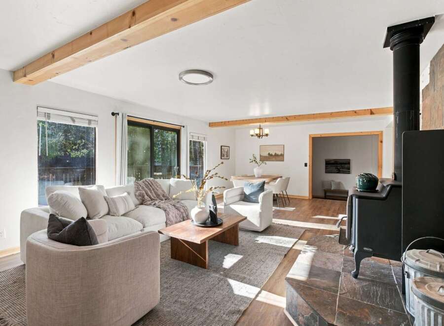 Experience rustic charm and modern comfort in this inviting living space, featuring exposed wooden beams and a cozy wood-burning stove.