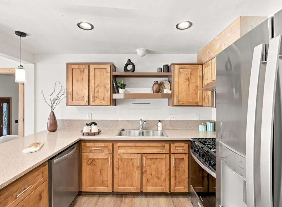 Discover this charming kitchen featuring warm, natural wood cabinetry and sleek stainless steel appliances, including a modern refrigerator and dishwasher.