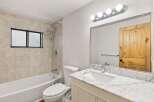 This beautifully updated bathroom features a spacious bathtub with a tiled shower surround and a convenient window for natural light.
