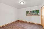 This inviting room features a large window offering serene views of the surrounding trees and a wooden fence.