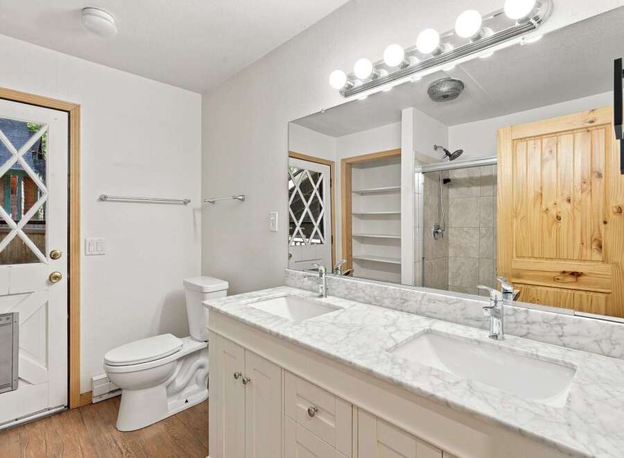 This bright and airy bathroom features a double vanity with a marble countertop, offering ample space for toiletries and morning routines.