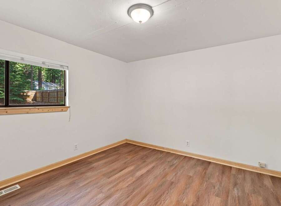 This inviting room features a large window offering picturesque views of the surrounding trees and a charming fence.