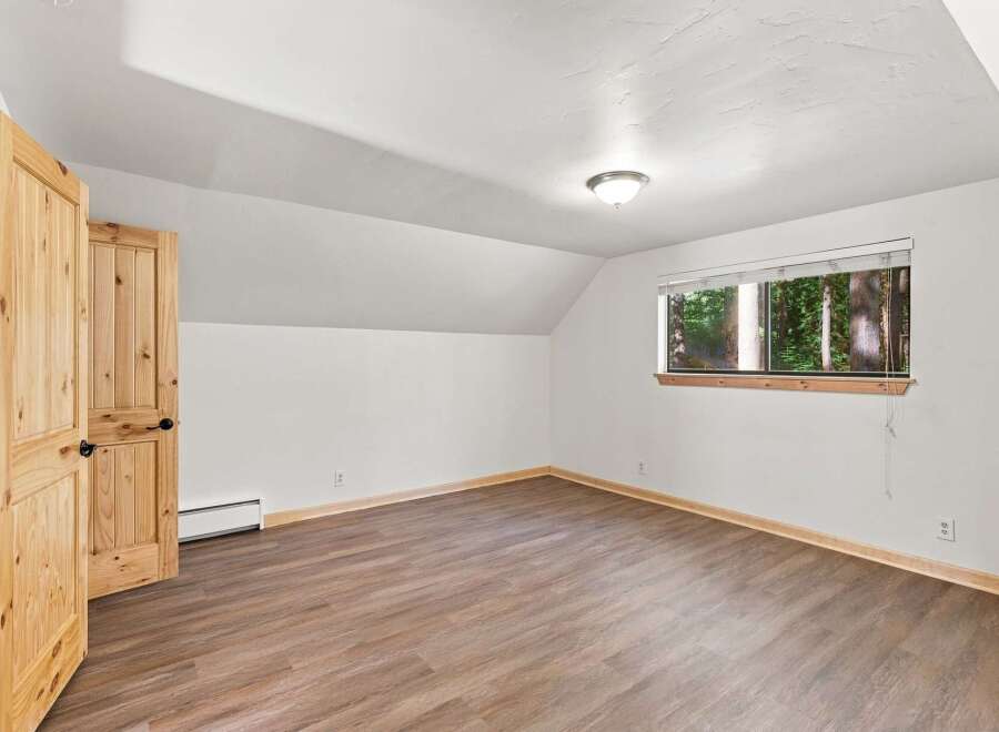 Discover this charming room featuring rustic wooden doors and a large window offering serene forest views.