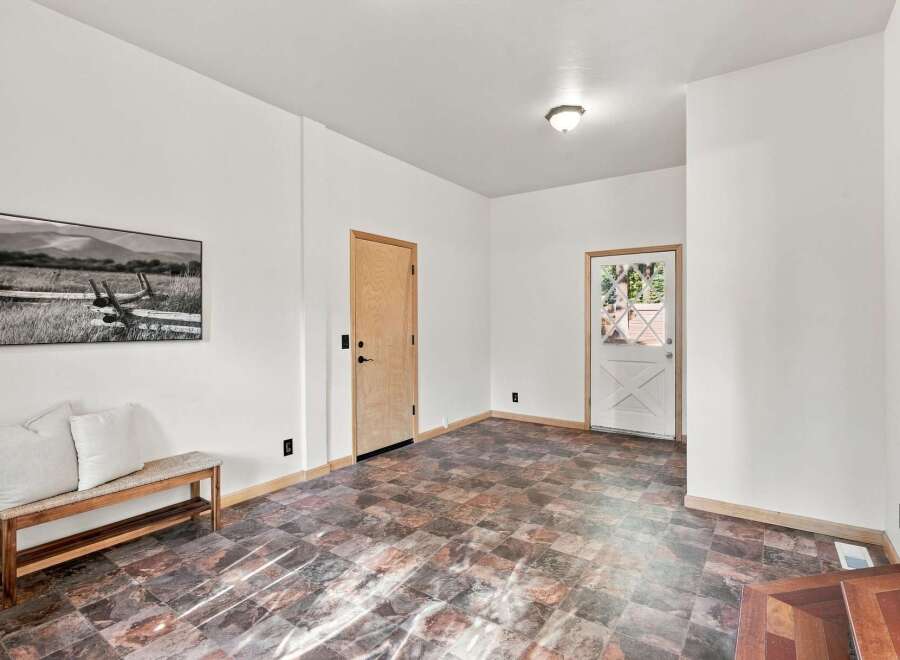 Step into this inviting entryway featuring a charming wooden bench with plush cushions, perfect for a moment of rest.