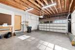This spacious garage offers ample room for vehicles and storage, featuring a durable concrete floor and exposed wooden beam ceiling.