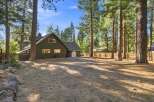 Nestled amidst towering pine trees, this charming home offers a serene retreat with its rustic exterior and spacious backyard.