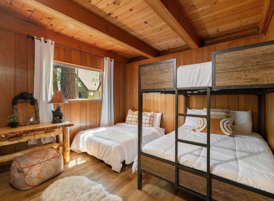 This charming cabin bedroom features a cozy bunk bed setup and a separate twin bed, perfect for accommodating family or guests.