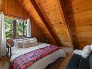 Experience cozy cabin living in this charming bedroom featuring a comfortable bed adorned with a rustic plaid blanket and plush pillows.