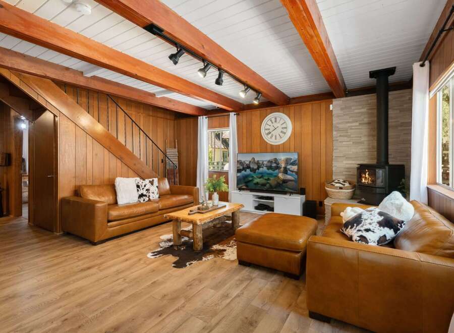 Experience rustic charm in this cozy living room, featuring warm wood paneling and exposed beams.
